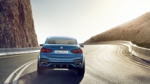 Вид сзади на синий BMW X4 на идеально ровном асфальте